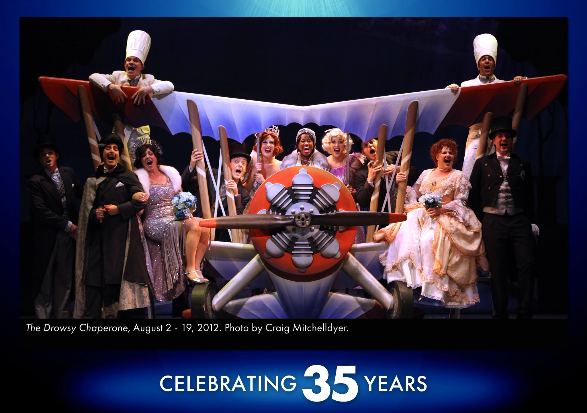 The Drowsy Chaperone A photo of the cast of The Drowsy Chaperone all piled in and on a setpiece that looks like a colorful 1930s biplane as they all sing out to the audience.