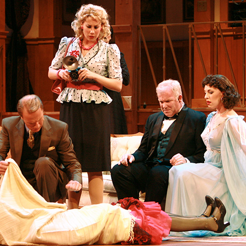 A photo from The Case of the Dead Flamingo Dancer. The cast is looking down at the comically stiff legs of a victim sticking out of the bottom of a bedsheet.