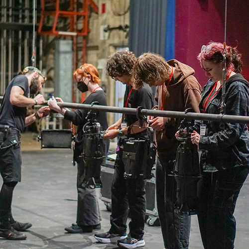 A photo of our 2026 interns learning how to properly rig a stage light.